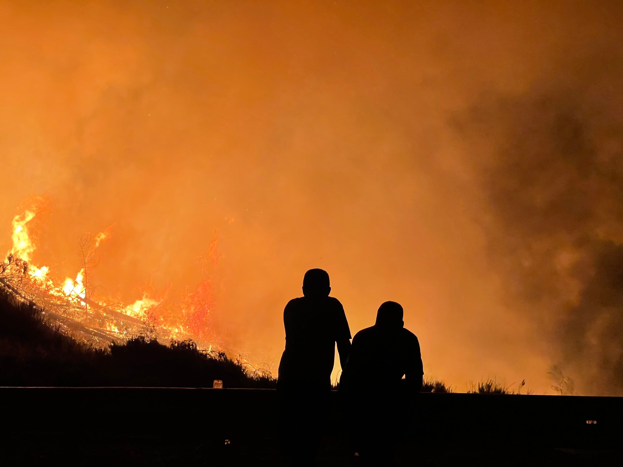 mensen kijken naar een vernitegende bosbrand