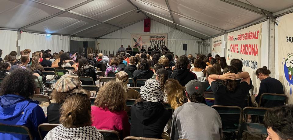 en zaal vol met jongeren luisteren op het jongerenkamp
